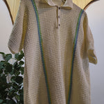 Beige crochet sweater with green accents on a hanger against a neutral background
