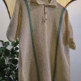 Beige crochet sweater with green accents on a hanger against a neutral background